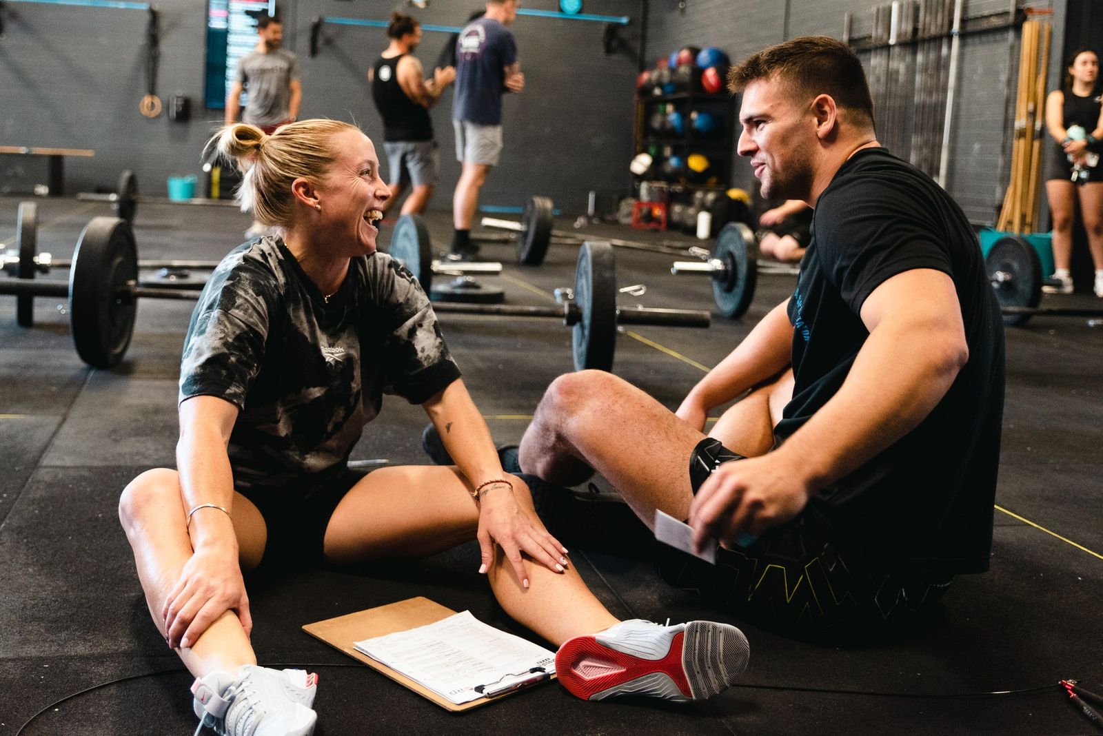 Two Grandstand members sharing a laugh on the gym floor after a workout