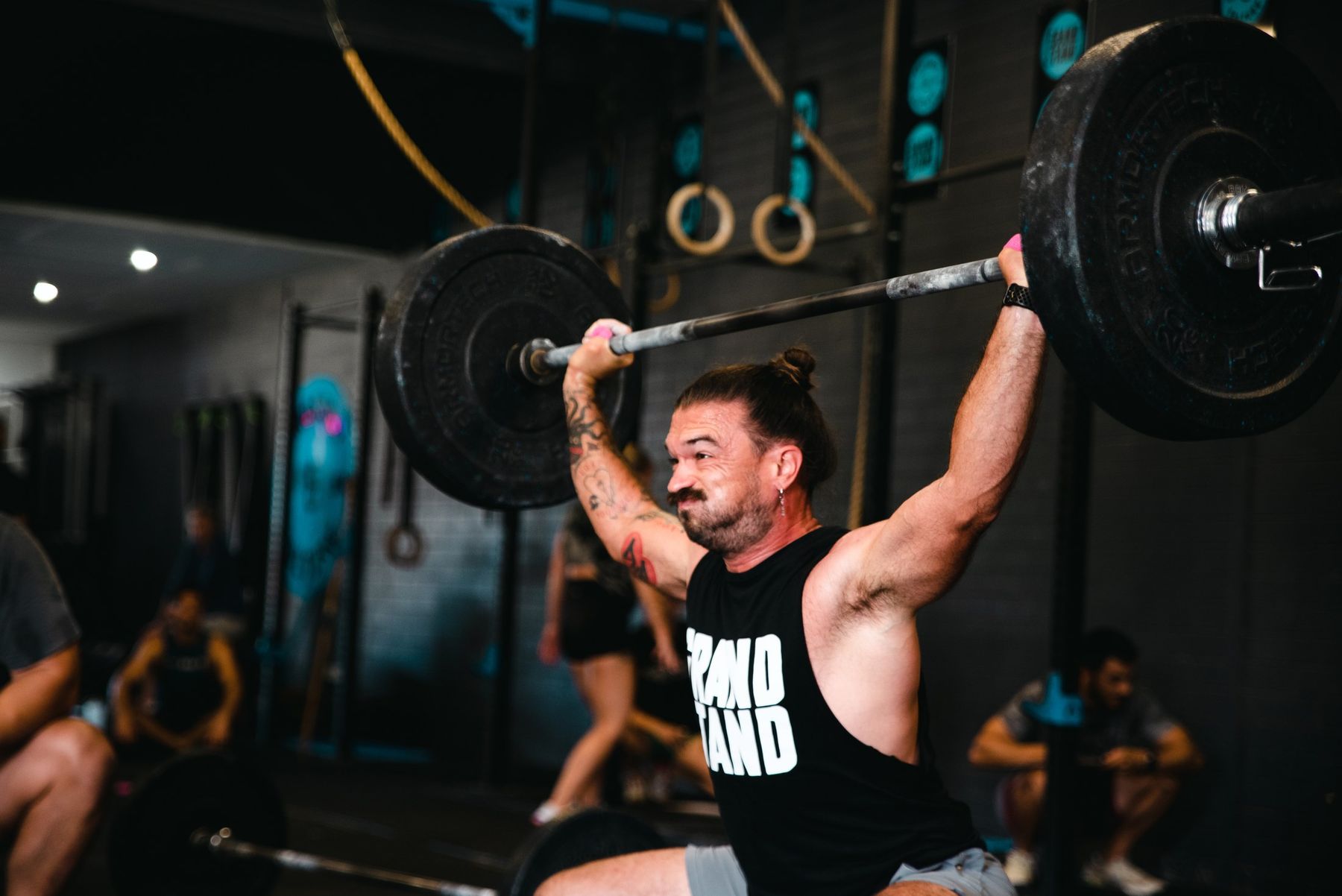 Grandstand member grinding out an overhead lift while the class cheers him on
