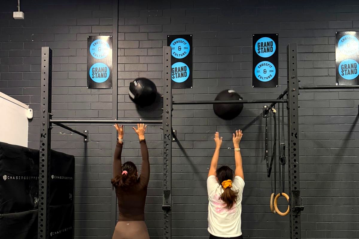 Members hitting wall balls in front of the Grandstand branded wall in a Hyrox-style session in Perth